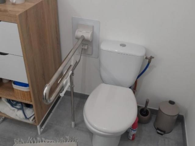 Pose d'une barre d'appui relevable sur pied à côté des toilettes 